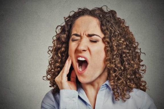 Woman with her mouth open and holding her jaw