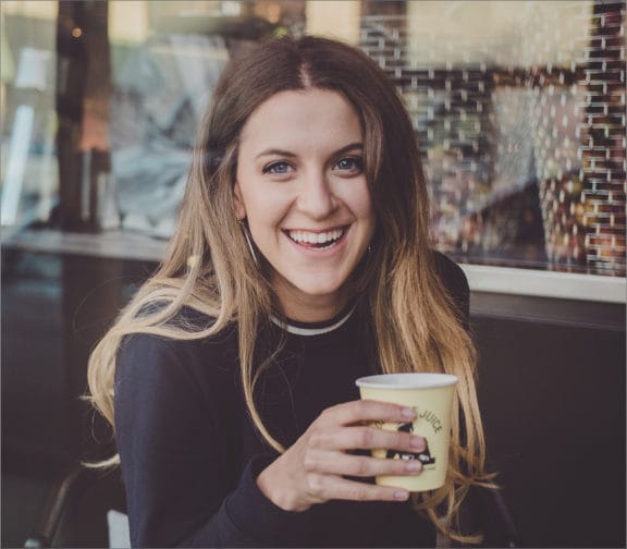 Woman sitting in front of a coffee shop enjoying her coffee