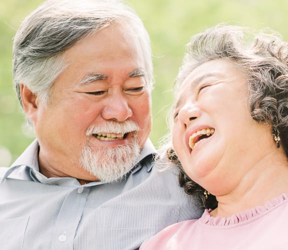 Mature couple sitting on a park bench looking into each others eyes and smiling