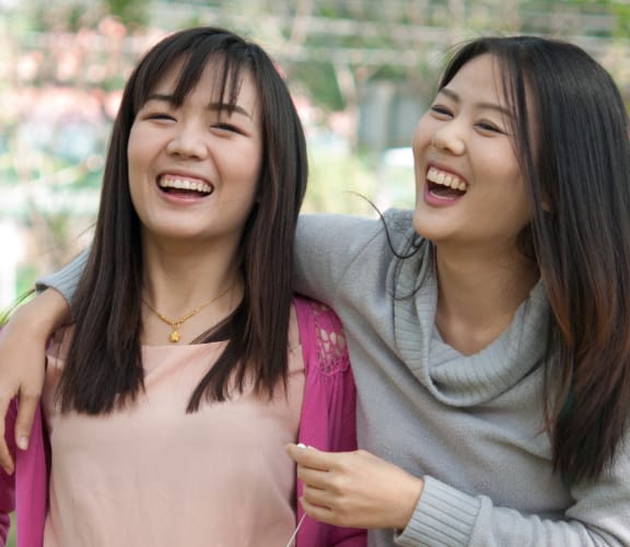 Two women in a park holding each other and laughing