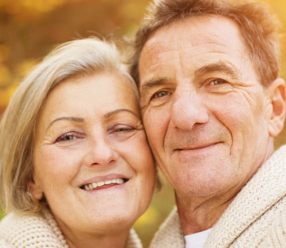 Mature couple standing outside while the sun sets in the forest