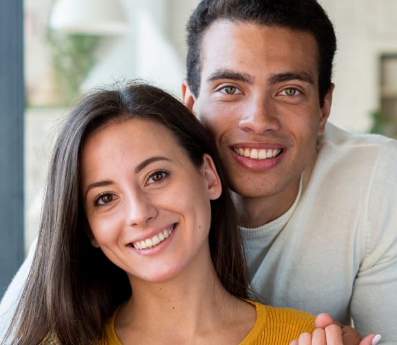 Man standing behind woman sitting on couch and embracing her