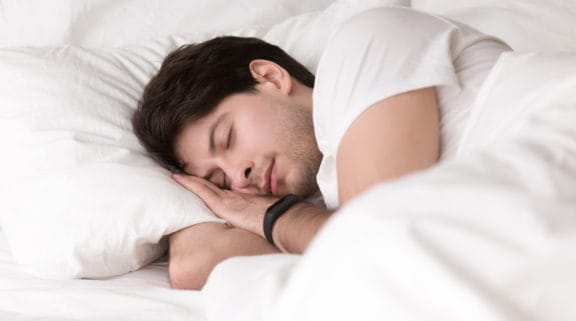 Man peacefully asleep with his head on his hands and pillow